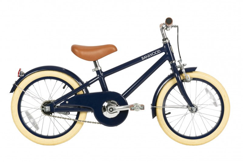 The Banwood Classic Children’s Bicycle, shown in navy blue with cream tires, brown saddle, fenders, and chain guard, is featured in side profile against a white background.