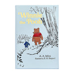 Graphic Image’s “Winnie the Pooh” book cover features Pooh and Piglet walking under trees—a charming illustration from the classic tale.