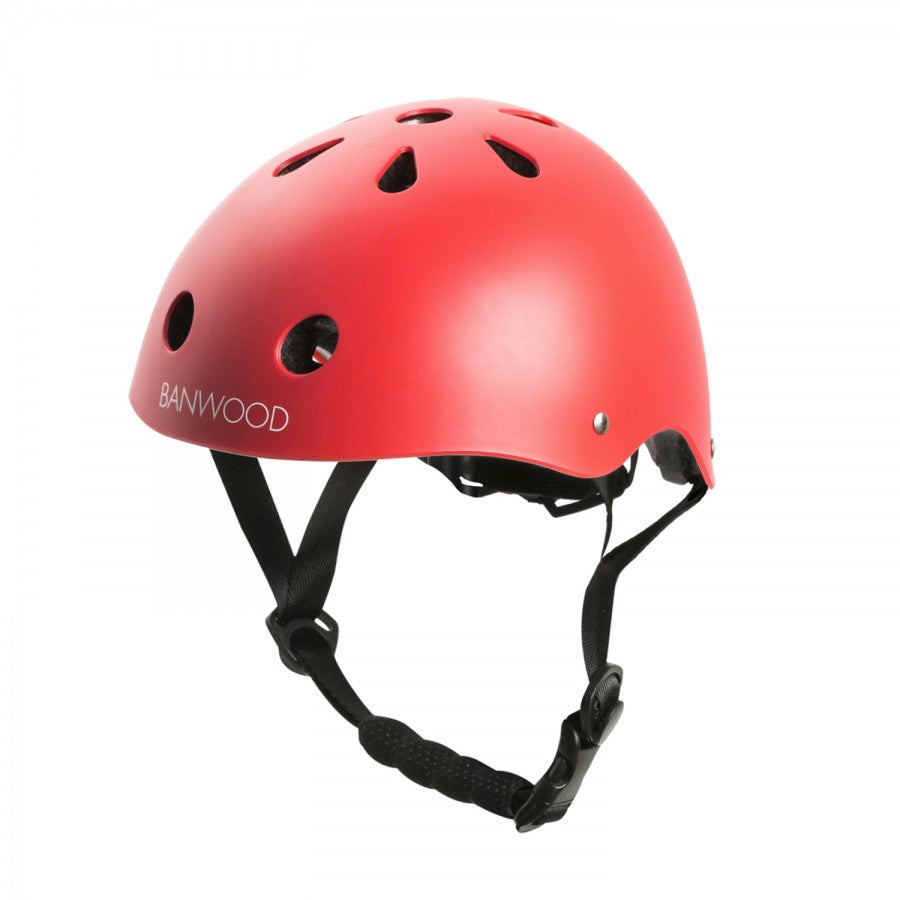 Banwood children's helmet with a red ABS hard-shell, black adjustable chin strap, and ventilation holes. Features a convenient dial fit adjustment for a snug fit, with the brand name "Banwood" visible on the side.