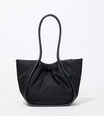 The Proenza Schouler Large Ruched Puffy Nylon Tote in black features a structured curved handle, gathered top, and gold-tone logo stamp, shown against a plain white background.