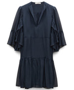 The Love of Lightness Dress by Dorothee Schumacher is a flowy navy blue silk dress with layered ruffle sleeves and a tiered skirt.