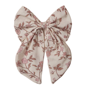 The Noralee Everly Bow is a large beige bow with a pink floral print, two long ribbon tails, and a rose gold alligator clip—an elegant baby hair accessory displayed on a white surface.