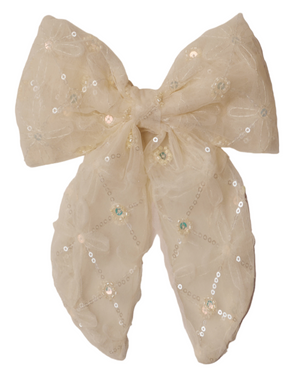 The Noralee Everly Bow, a large sheer cream accessory adorned with rose gold sequins and floral embroidery, is displayed against a light beige background.
