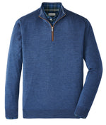 Peter Millar Autumn Crest Suede Trim Quarter-Zip in blue, featuring a brown zipper pull, is layered over a blue and green plaid collared shirt and displayed on a white background.