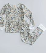 Timo & Violet Kids' The Two Piece Pajamas feature long sleeves and a multicolored Happy Monkey and lively plant print on a white background, shown flat on a light surface.
