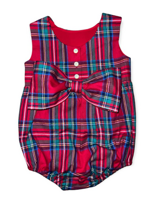 The Brown Bowen & Company Lolli Bow Back Bubble in Tybee Tartan is a festive red and blue plaid baby romper with a charming silhouette, three white chest buttons, and a large matching bow at the waist.