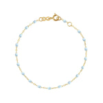 The Classic Gigi Bracelet 6.7" by Gigi Clozeau is a stunning 18 carat yellow gold piece, featuring small light blue beads and a simple clasp mechanism.