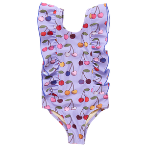 The Pink Chicken Girls' Katniss Suit is a purple one-piece swimsuit featuring a lively cherry pattern and cute ruffled sides, making it the ideal addition to your beach day outfit.