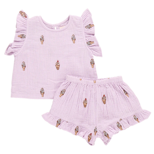 The Girls' Roey 2-Piece Set by Pink Chicken is a charming toddler outfit made from double cloth cotton gauze. It features a sleeveless top and shorts with ice cream cone patterns, enhanced with ruffle details on the sleeves and hem.