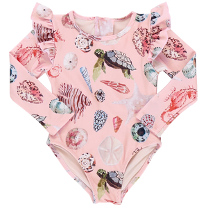 The Girls' Rachel Suit by Pink Chicken is a pink long-sleeve swimsuit featuring watercolor shells, turtles, and coral prints. It includes ruffled shoulders and offers sun protection with its ocean-themed design.