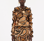 Model wears the Ulla Johnson Sunara Pullover—a coordinated top and skirt set made from Italian cotton with an orange, black, and beige paisley print—shown against a plain white background.