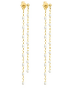 The Dangling Gigi Earrings by Gigi Clozeau feature 18-carat gold long chains adorned with small white beads, offering a touch of elegance.