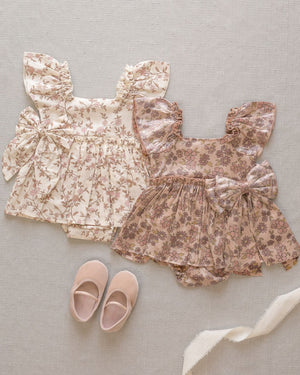 Two Noralee Baby Girls' Margot Rompers in cream and dusty pink, each with floral prints and large bows, are paired with pink baby shoes—a perfect special occasion outfit inspired by the charming Margot Romper.