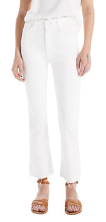 A person is wearing The Hustler Ankle Fray jeans by Mother with a white top and brown sandals, revealing a small tattoo on the left hand's ring finger.