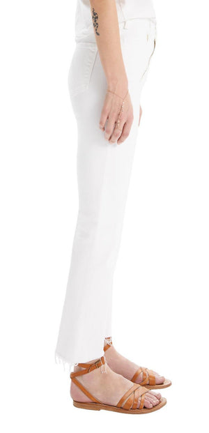 A person showcases their forearm tattoo while standing sideways on a white backdrop, wearing Mother’s The Hustler Ankle Fray. The white high-waisted denim pants with a subtle frayed hem and brown sandals create a sleek yet edgy silhouette.