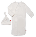 The Magnetic Me Baby Love Lines Gown + Hat Set is a white long-sleeve newborn outfit with side snap buttons, matching knot-top hat, subtle vertical stripes, red fabric tags, and made from soft organic cotton for your baby's comfort.