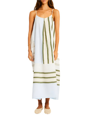 Woman wearing the Lemlem Nia Slip Dress, a hand-woven cotton piece featuring vertical and horizontal green stripes, paired with woven slip-on shoes.