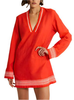 A person confidently poses with one hand on their hip, wearing the chic lemlem Raey Dress. Adorned with sheer stripes and white geometric trim from Lemlem, it perfectly blends elegance and style.