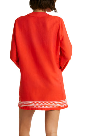 The lemlem Raey Dress by Lemlem features a red long-sleeve tunic with white decorative trim at the bottom, resembling a chic mini dress. Its elegantly hand-woven design from Ethiopia adds an exquisite touch to this striking attire.