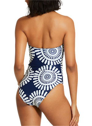A woman models the Lemlem Dinha One Piece from the back, showcasing its flattering, sleek neckline and navy blue and white circular geometric pattern.
