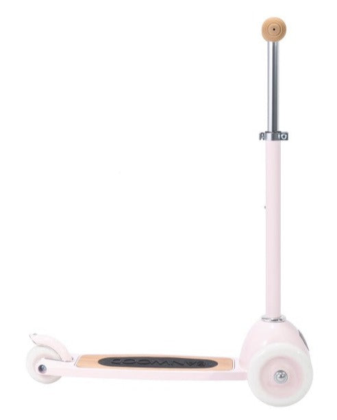 The Banwood Scooter is a pink toy with two white wheels, a wooden footboard featuring the Banwood logo, and an adjustable handlebar, ideal for developing fine motor skills and balance.