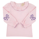 The Girls' Long Sleeve Ramona Ruffle Shirt by The Beaufort Bonnet Company features a light pink design with a ruffled collar, purple trim, and sweet bow accents—ideal for a stylish back-to-school outfit.