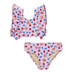 The Girls' Katniss Bikini by Pink Chicken is a charming pink two-piece swimsuit with ruffled shoulders, featuring a playful fruit pattern of apples, strawberries, and blueberries.