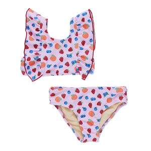The Girls' Katniss Bikini by Pink Chicken is a charming pink two-piece swimsuit with ruffled shoulders, featuring a playful fruit pattern of apples, strawberries, and blueberries.