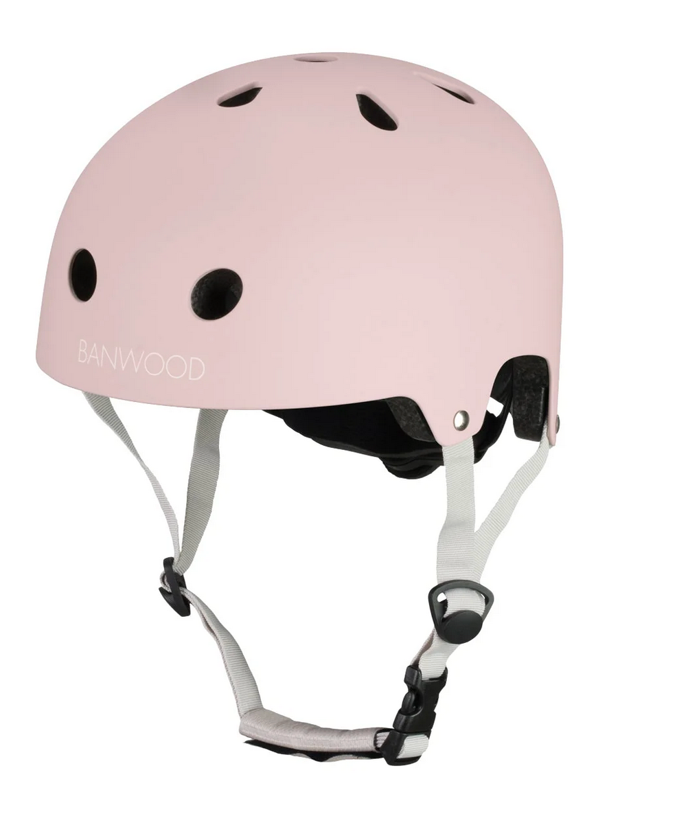 The Banwood Eco Helmet features a light pink classic design, ventilation holes, adjustable white straps, and a black buckle—part of the brand's eco collection.