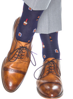Brown leather dress shoes with a cap toe are stylishly paired with Dapper Classics' Bourbon Bottle Mid Calf Socks in Classic Navy and Burnt Orange. These dark blue socks add a touch of sophistication to grey pants, known for durability and comfort with breathable materials.