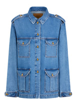 The Nariida Sahariana by Blaze Milano is a safari-inspired denim jacket with front buttons and flap pockets, highlighted by gold button accents and shoulder epaulettes for an adventurous touch.