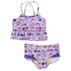 The Girls' Joy Tankini by Pink Chicken is a purple two-piece swimsuit with a charming cherry pattern, featuring a sleeveless top with a ruffled hem and matching bottoms, embodying carefree joy.