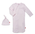 The Magnetic Me Baby Love Lines Gown + Hat Set features a light pink organic cotton newborn sleeper gown with long sleeves and magnetic closures, paired with a matching knotted hat, both displayed on a white background.