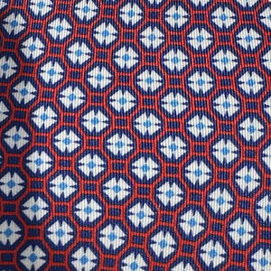 The Maltese Cross Tie by Robert Jensen features a blue, red, and white geometric pattern with repeated hexagons and diamond motifs, hand-stitched in Italy from fine silk.