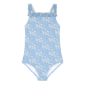 Laid flat on a white background, the Minnow Girls' Capel Ruched Strap One Piece is a light blue swimsuit with a white floral print made from Liberty Fabric, featuring ruffled straps and a fully lined design.