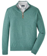 The Peter Millar Artisan Crafted Cashmere Flex Quarter-Zip in green, inspired by classic British Isles knitwear, is layered over a light gray plaid collared shirt and displayed flat on a white background.