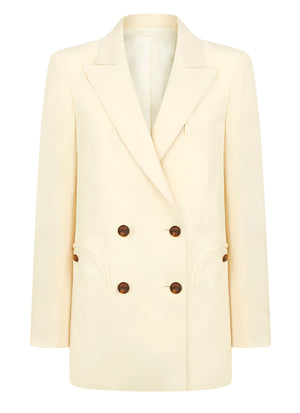 The Savannah Everyday Blazer by Blaze Milano is a classic cream-colored piece featuring a double-breasted design with brown buttons, peak lapels, two front pockets, and crafted from a luxurious silk and linen blend.