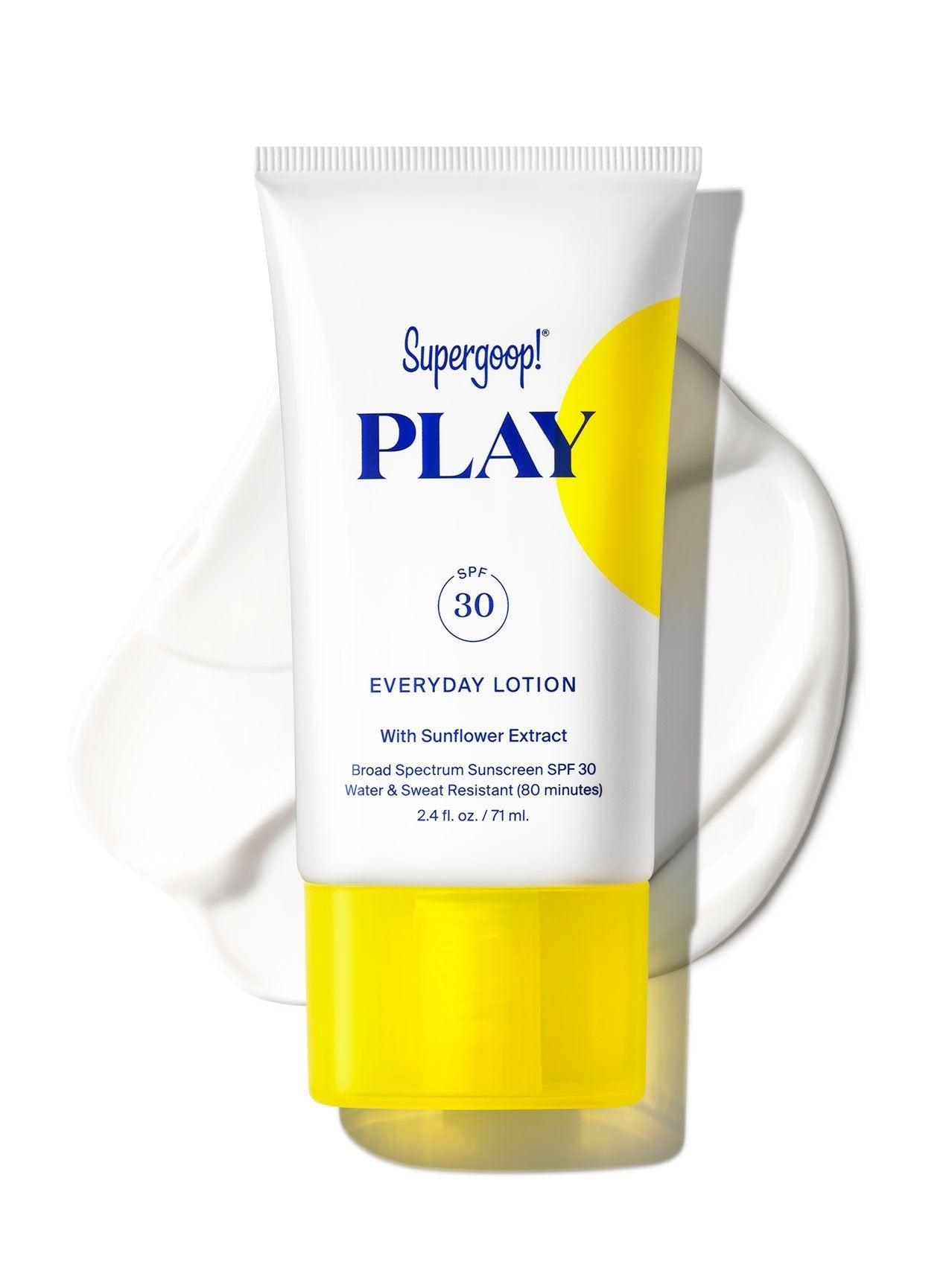 A tube of Supergoop Play Everyday Lotion with Sunflower Extract SPF 30 (2.4 oz) rests on a white surface, with a smear of the hydrating sunscreen lotion behind it.