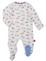 The Magnetic Me Baby Boys' Footie is a white onesie with colorful construction vehicles, made from eco-friendly TENCEL™ modal, featuring long sleeves and blue fabric on the right foot.