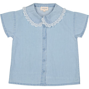 The Girls College Tunic by Louis Louise is a light blue, short-sleeve chambray shirt with a button-down front and a Peter Pan collar adorned with elegant broderie anglaise trim.