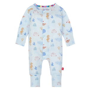 The Baby Modal Convertible Coverall by Magnetic Me is a light blue onesie made from eco-friendly TENCEL™ modal, with a colorful pattern of seahorses, whales, and sea plants. It features long sleeves and a convenient front snap closure.