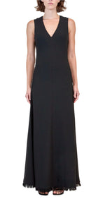 A woman faces forward in the Simkhai Lowri Dress, a sleeveless, floor-length black gown featuring a V-neckline and fluid silhouette, set against a plain light background.
