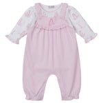 The Kissy Kissy Baby's Giraffe Grace Overall Set features pink overalls with ruffled straps and a giraffe print long-sleeve shirt, plus snap buttons at the legs and a chest ruffle detail.