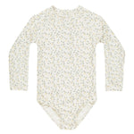 The Rylee & Cru Girls' Delphine Rashguard features long sleeves, a cream base with light green and yellow floral print, and provides sun protection for your little one. Shown laid flat on a white background.
