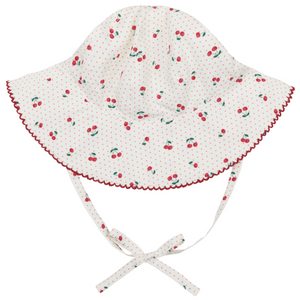 The Minnow Baby Girls' Summer Cherries Sun Hat features a red and green cherry print, red scalloped brim, and chin straps tied in a bow. Made from soft cotton for comfort and sun protection.