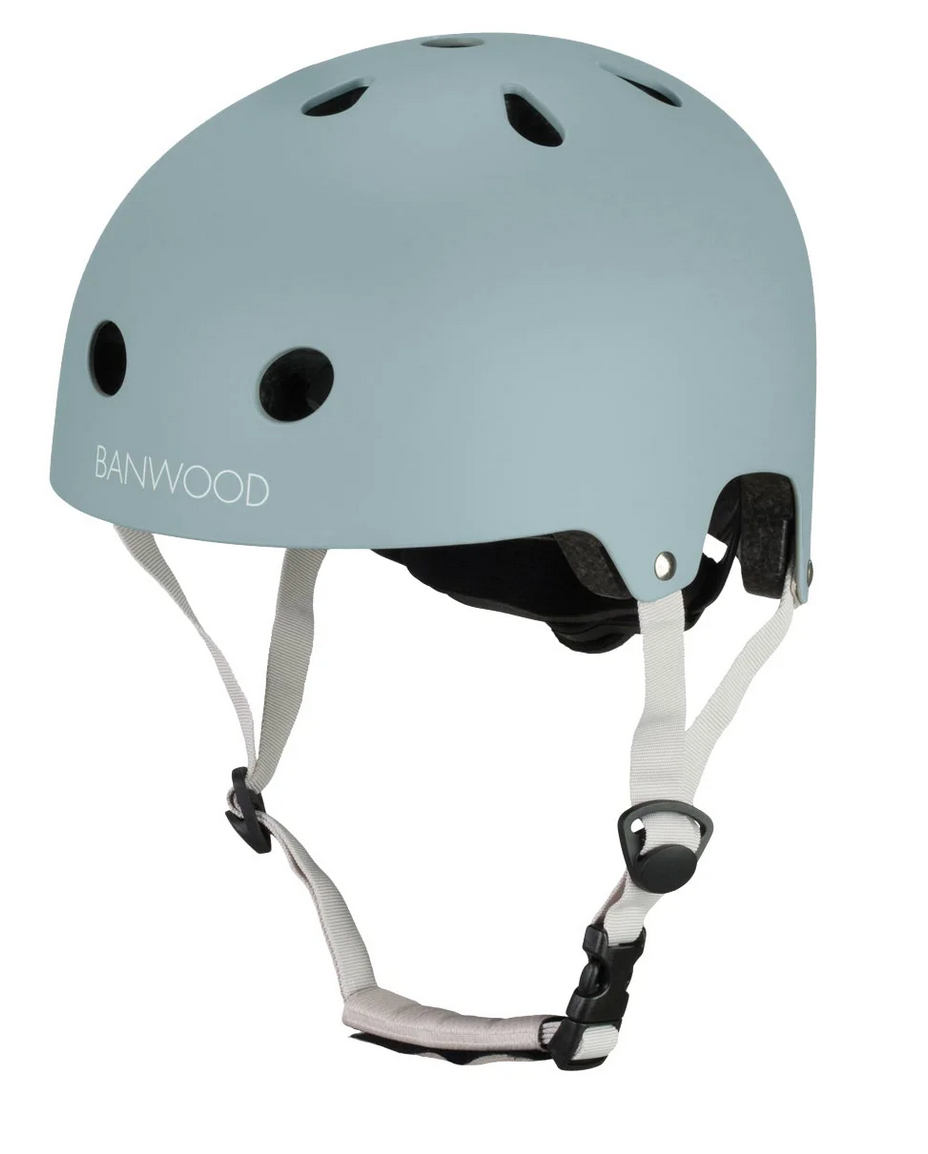 The Banwood Eco Helmet, shown in light blue with ventilation holes, white adjustable chin straps, and a black buckle, is displayed against a plain white background.