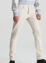 A person is wearing AG Jeans Tellis Selvage in light denim, paired with a pale blue and white striped sweater and black shoes, standing against a plain light background.