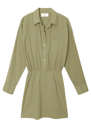 The Loulou Dress by Xirena is an olive green cotton poplin mini shirtdress featuring long sleeves, a collar, and button-up front. It includes a breast pocket, gathered waistline, and elastic back for comfort.