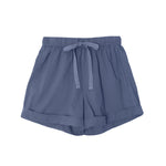 The Declan Short by Xirena is a light blue, lightweight woven cotton short with an elastic drawstring waist, side seam pockets, and folded hems, shown laid flat on a white background.