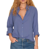 A person wearing the Xirena Beau Shirt, a loose-fitting cotton poplin menswear-inspired top with rolled cuffs, paired with blue jeans and one hand in a pocket.